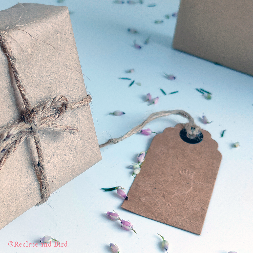 photo of a jewellery box wrapped in brown paper with brow string and a little brown kraft tag with the logo of Recluse and Bird embossed in it